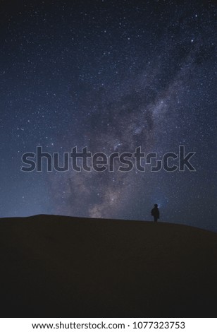 Landscape with Milky Way. Night sky with stars and silhouette of a standing  man on sand hill.