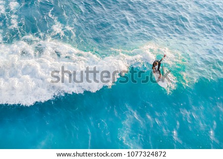 Surfer at the top of the wave in the ocean, top view Royalty-Free Stock Photo #1077324872