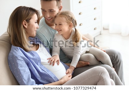 Young pregnant woman with her family at home Royalty-Free Stock Photo #1077329474