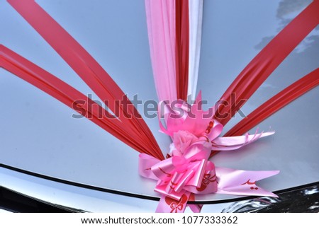 Red and pink ribbons on the hood of a gray car - decoration for a wedding, Negev, Israel