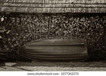 a green boat stands at a pile of chopped wood