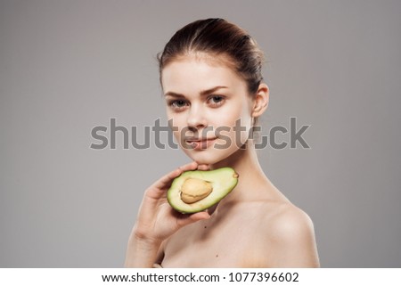 woman with green fruit in her hand, avocado                        