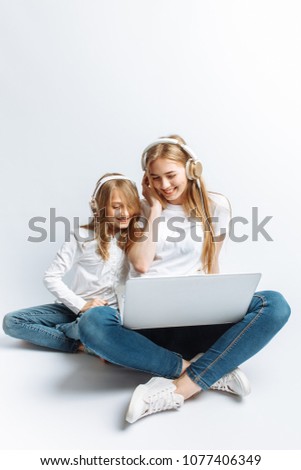 A sister or a young mother with her daughter watching a movie on my laptop, fun, laughing, Studio