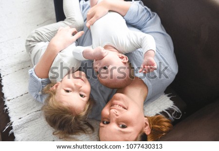 Picture of young mother hugging two little children, closeup portrait of happy family, cute brunette female with daughter and son indoor