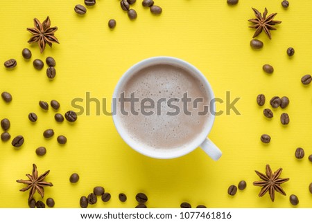 Cup on the saucer with coffee and milk foam Coffee beans Anise Cinnamon on a Bright Yellow Background.