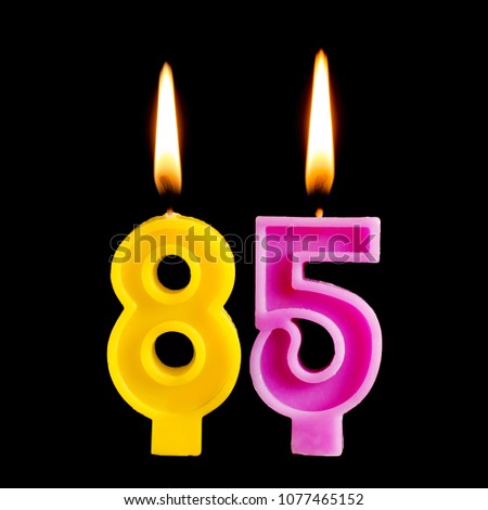 Burning birthday candles in the form of 85 eighty five figures for cake isolated on black background.