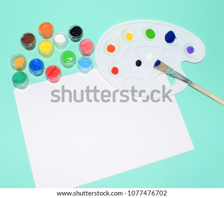 A photo of school supplies. Multicolored palette of gouache paints.
