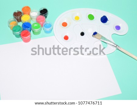 A photo of school supplies. Multicolored palette of gouache paints.