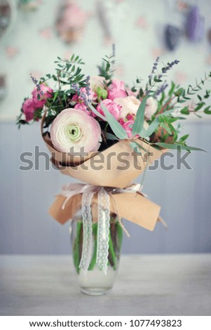 a tender bouquet with roses, grass and other flowers is wrapped in paper in a vase on the table