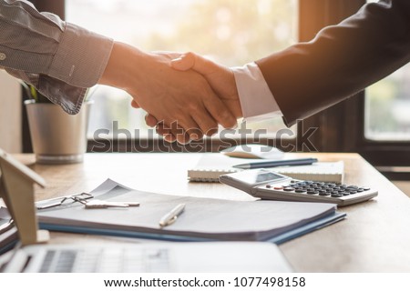 Top view hands of agent and client shaking hands after signed contract buy new apartment. Royalty-Free Stock Photo #1077498158