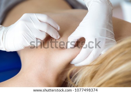 Close-up of young physiotherapist doing a trigger point injection in patient back. Royalty-Free Stock Photo #1077498374