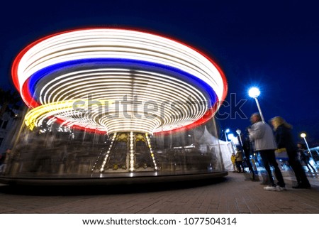 Abstract, long exposure shot of spinning Children's vintage Carousel at an amusement park in the evening and night illumination. Beautiful, bright carousel in Alicante, Spain 