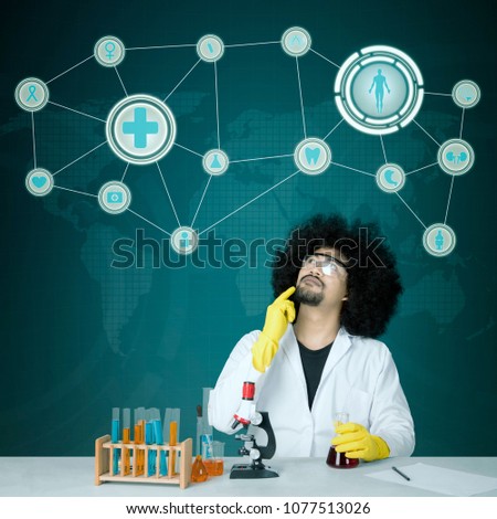 Photo of pensive male scientist looking up while doing chemical research. Shot with virtual screen background