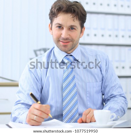 closeup.handsome businessman signing a document, sitting behind a Desk