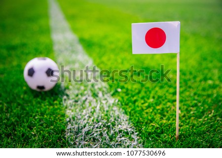 Japan national Flag and football ball on green grass. Fans, support photo, edit space. 