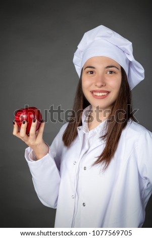 Beautiful Turkish young female chef keeping an apple on her hand