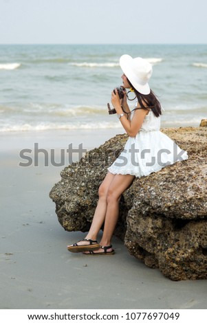 Asian tourist woman taking photo on the beach.