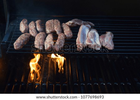 Raw sausages and pork chops on  hot barbecue