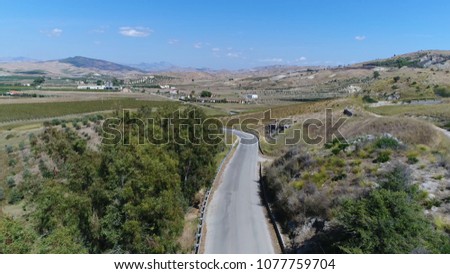 Aerial picture of rural road moving downwards showing trees vineyard and mountain horizon in background beautiful summer day