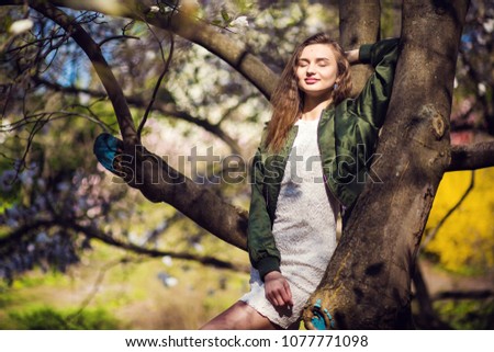 Young beauty girl posing in garden with magnolia blossom
