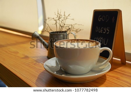 A cup of coffee in the moring with blessing message "God bless you" on a blackboard in warm lighting tone
