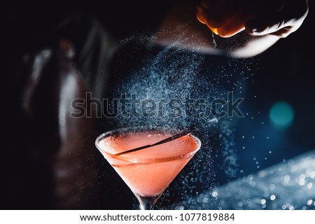 Large cocktail in martini glass with droplets of spray is prepared by barman. Royalty-Free Stock Photo #1077819884