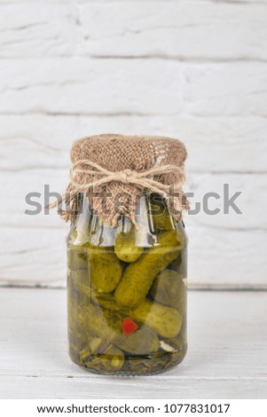 Pickled cucumbers in a jar. Stocks of food. Top view. On a wooden background. Copy space.