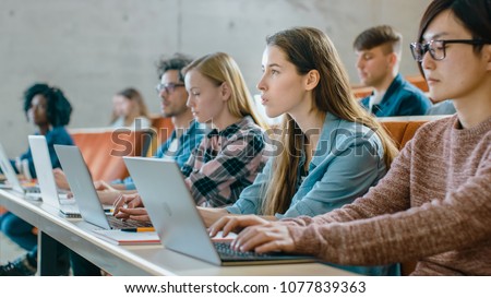 Large Group of Multi Ethnic Students Working on the Laptops while Listening to a Lecture in the Modern Classroom. Bright Young People Study at University. Royalty-Free Stock Photo #1077839363