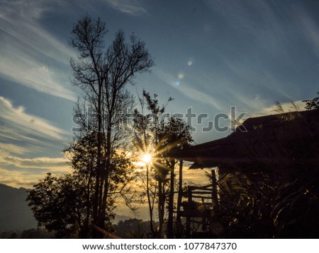 Silhouette sunset light with wooden cottage on the hill 