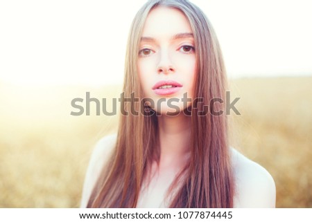 Portrait of a attractive woman over golden wheat field in summer day.