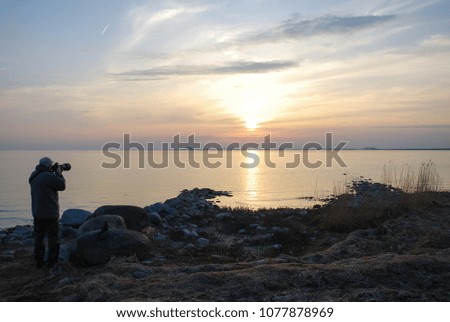 Male photographer capturing a beautiful sunset by the sea