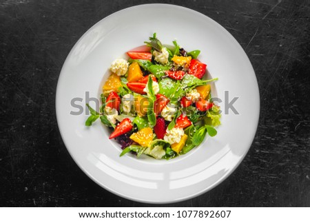 summer tasty healthy dietetic salad with strawberry orange goat cheese leaves salad mint sesame in white plate on the dark background 