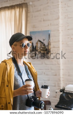 girl tourist in a cafe with plastic cups of coffee and a camera on the neck, the concept of travel, coffee with him