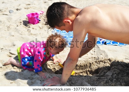 Close - up of a guy and a little kid playing on the beach, in the sand they dig a hole, build castles