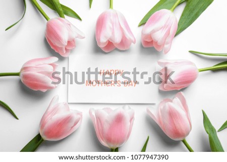 Beautiful tulips and greeting card with words "Happy Mother's Day" on light background, top view