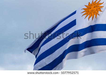 close up of national flag of Uruguay blowing in the wind with blue sky in background