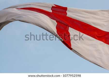 national flag of England St Georges flag blowing in the wind with blue sky in background
