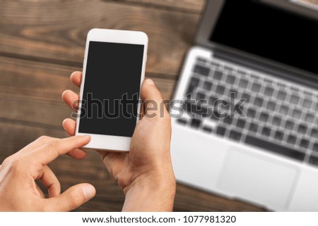 Hand working on phone and laptop