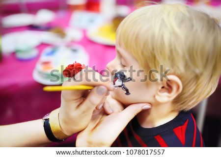 Face painting for cute little boy during kids merriment. Face paint for "Pirates" theme on birthday party. Preschooler kids celebrating party in entertainment center