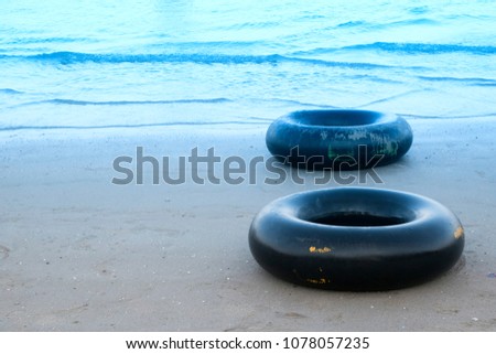 Black life ring on the beach, Life ring on the sand at beach in Thailand.
Blue color tone.
Thailand beach travel background concept 