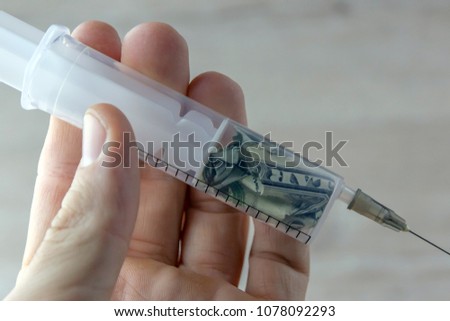 monetary treatment: a syringe with a dollar inside, in the person's hand
