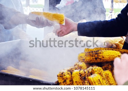 Hand' s merchant sending corn boiled to woman's hand at store sale corn grill with smoke around picture, popular snack street food in Istanbul Turkey