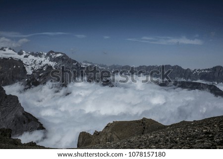 Hike in Swiss Alps during a sunny day with a view on impressive cliffs, blue sky  and alpine meadows