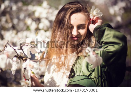 Young beauty girl posing in garden with magnolia blossom