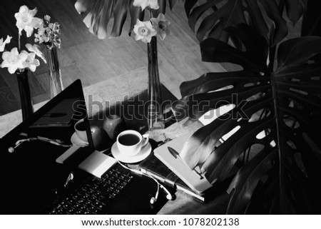 Working at home with cup of coffee surrounded with flowers, black and white photography.