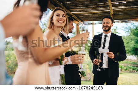 Best man performing speech for toast at wedding reception. Bride and groom listening to a speech at their wedding reception. Royalty-Free Stock Photo #1078245188
