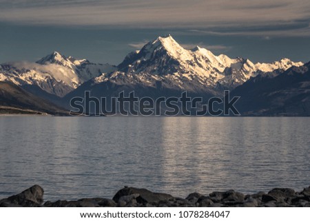 Sunrise over Pukaki glacier lake with turquoise blue water and mountains landscape. Winter mountain landscape with snow and glacier lake. Pukaki lake at Aoraki - Mount Cook National Park, New Zealand.