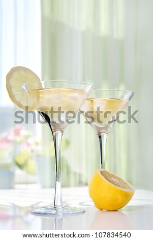 Martini alcohol cocktail with yellow lemon on white table