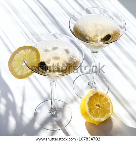 Top view of martini alcohol cocktail with yellow lemon on white with shadows