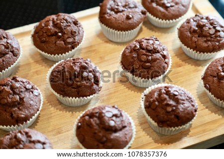 fresh from the oven chocolate chip muffins on wooden cutting board